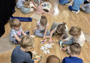 Dzieci w grupach układają puzzle