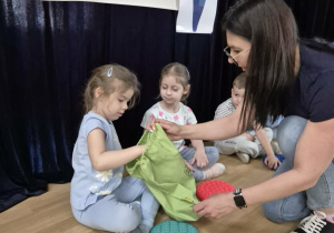 Dziewczynka wkłada rękę do worka trzymanego przez nauczycielkę