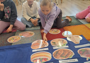 Dzieci układają potrawy na wielkanocny stół.