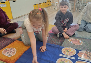 Dzieci układają potrawy na wielkanocny stół.