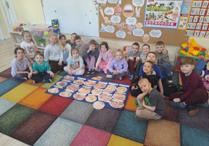 Dzieci prezentują ułożone potrawy na stole wielkanocnym.