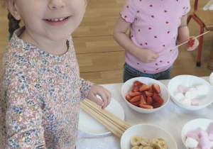 Dziewczynka macza piankę w czekoladowej fontannie.