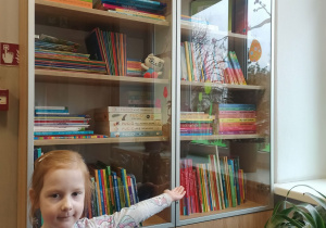 dziewczynka wskazuje na przedszkolną biblioteczkę