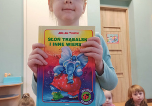 dziewczynka pozuje do zdjęcia z książką