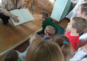 dzieci patrzą na książkę napisaną alfabetem braille'a