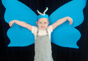 dziecko pozuje do zdjęcia na tle skrzydeł