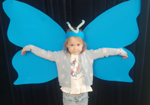 dziecko pozuje do zdjęcia na tle skrzydeł