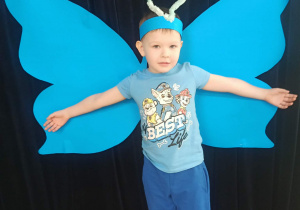 dziecko pozuje do zdjęcia na tle skrzydeł