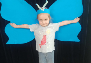 dziecko pozuje do zdjęcia na tle skrzydeł