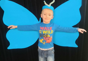 dziecko pozuje do zdjęcia na tle skrzydeł