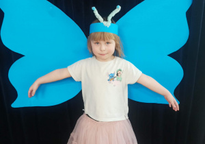 dziecko pozuje do zdjęcia na tle skrzydeł