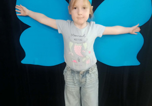 dziecko pozuje do zdjęcia na tle skrzydeł