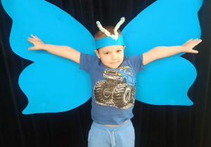 dziecko pozuje do zdjęcia na tle skrzydeł