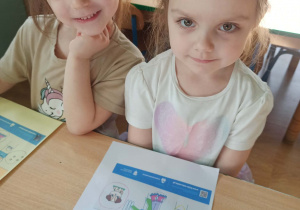 dziewczynki pozują do zdjęcia z wykonaną kartą pracy