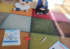 dzieci siedzą na dywanie