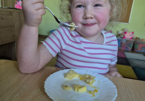 Uśmiechnięta dziewczynka je sałatkę owocową