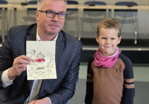 Prezydent oraz chłopiec pozują do zdjęcia, prezydent trzyma w ręku kartkę od dzieci