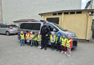 Dzieci razem ze strażnikiem miejskim pozują do zdjęcia przy samochodzie straży miejskiej