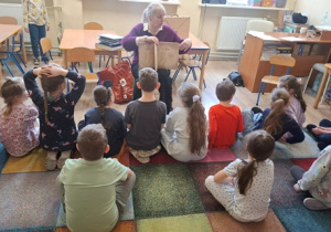 Dzieci siedzą na dywanie.