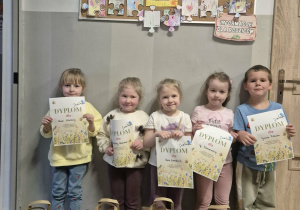 Pięcioro dzieci pozuje do zdjęcia trzymając dyplomy