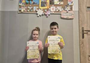 Dwoje dzieci pozuje do zdjęcia trzymając dyplomy