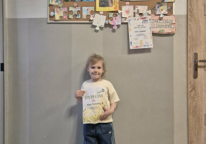 Dziewczynka pozuje do zdjęcia trzymając dyplom