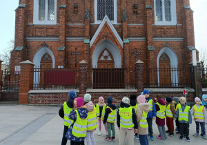 Dzieci biorą udział w spacerze ulicami miasta, obserwując najważniejsze budynki.