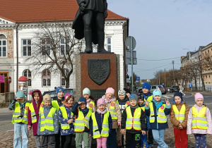 Dzieci biorą udział w spacerze ulicami miasta, obserwując najważniejsze budynki.