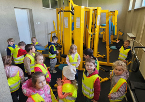 Dzieci oglądają sprzęty w siłowni.