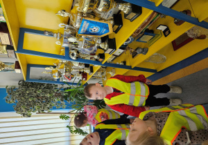 Dzieci oglądają puchary w sali konferencyjnej.