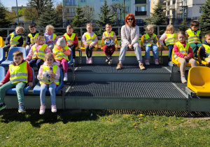 Dzieci wraz z nauczycielką siedzą na trybunach stadionu.