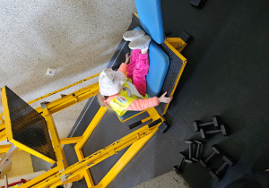 Dziewczynka ćwiczy na ławeczce do ćwiczeń.