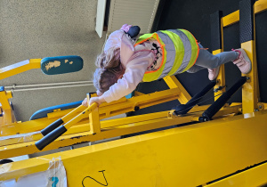 Dziewczynka ćwiczy na przyrządzie do ćwiczeń.