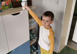 Chłopiec odkłada kubek na miejsce.