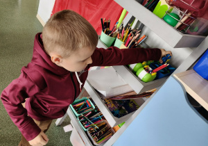 Chłopiec odkłada nozyczki na miejsce.