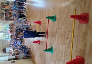 Dzieci w trakcie wykonywani konkurencji: przeskok obunóż przez laski gimnastyczne na różnych wysokościach