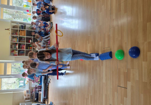 Hania Ł. w trakcie konkurencji: przejście po ścieżce sensorycznej z laska gimnastyczną.