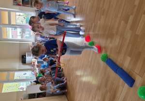 Dziewczynki w trakcie konkurencji: przejście po ścieżce sensorycznej z laska gimnastyczną.