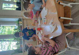 Dzieci malują farbami słoiki i butelki.