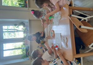 Dzieci malują farbami słoiki i butelki.