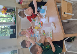 Dzieci malują farbami słoiki i butelki.