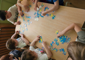 Dzieci układają puzzle z herbem Kutna.