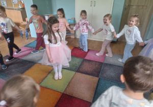 dzieci chodzą po kole wokół dziewczynki