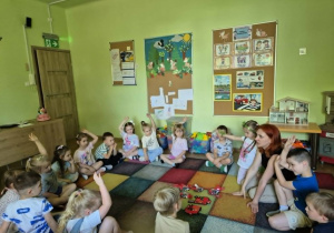 Dzieci siedzą z nauczycielką na dywanie