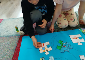 Dzieci umieszczają puzzle na drzewie różnorodności