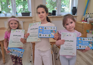Dziewczynki biorące udział w konkursie z dyplomami i upominkami.