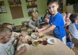 Dzieci przy stoliku przygotowują sobie kanapki