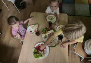 Dzieci przy stoliku przygotowują sobie kanapki