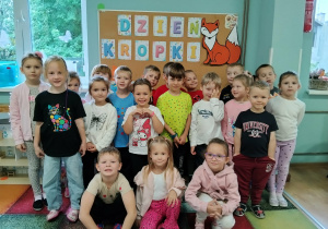 Dzieci stojące na tle napisu z okazji Dnia Kropki