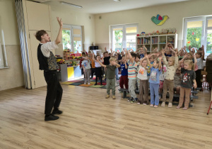 Dzieci na sali gimnastycznej naśladują taniec pokazany przez muzyka